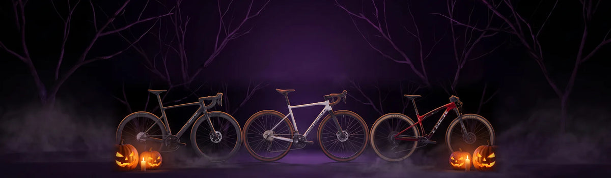 Tre biciclette in uno studio buio con zucche di Halloween